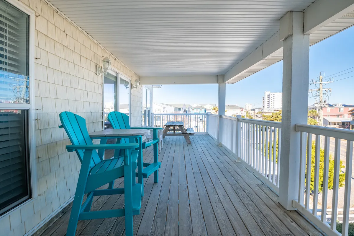 A welcoming outdoor deck with turquoise chairs and a wooden picnic table, open to a wide view of the surroundings. The space is ideal for group meals, lively gatherings, or simply relaxing with a book, capturing the fun, communal spirit described in the section.