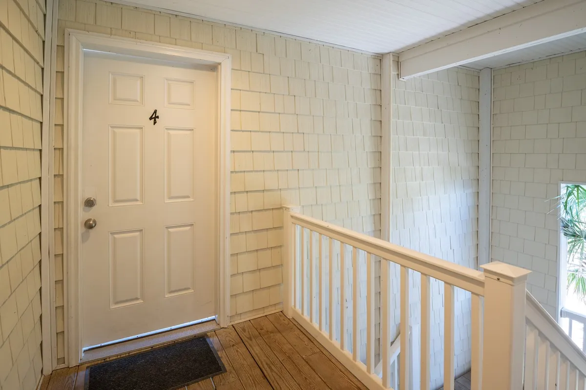 A bright entryway scene featuring a white door marked with the number 4, wooden railing, and light wooden flooring. The space feels welcoming and hints at arrival or departure, suggesting easy access to and from the property for adventures nearby.