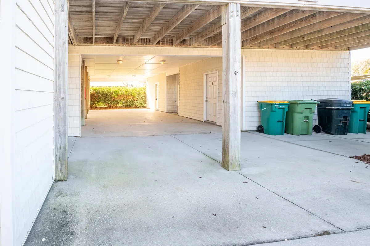 A covered open space with storage areas, garbage bins, and ample room, likely intended for parking vehicles or organizing outdoor equipment. The scene is functional and directly related to arriving from or preparing for outings.